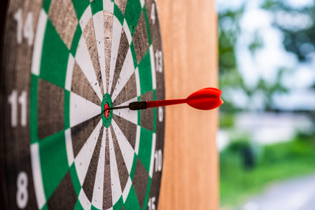 Red dart arrow in bullseye target on dartboardの写真素材
