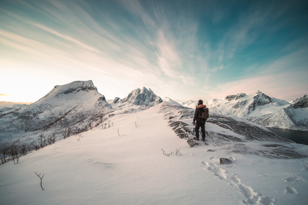 Mountaineer standing on top of snowy mountain at sunlight morningの写真素材
