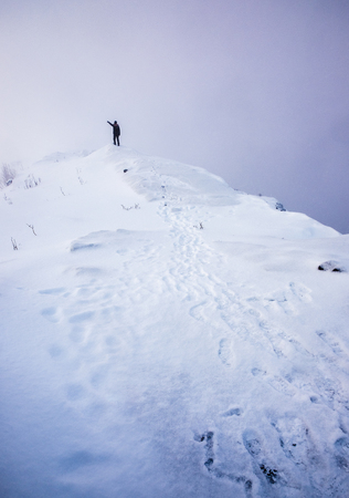 Man stand pointing on snow steep ridge with footprintの写真素材
