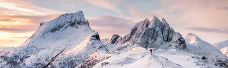 Panorama of Steep peak mountains with covered snow and mountaineer man backpacker stand aloneの写真素材