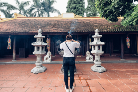 Rear of girl stand praying with incense at front ancient shrine for success in lifeの写真素材