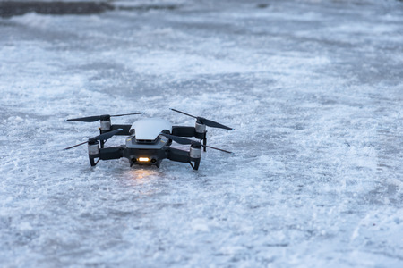 Drone Unmanned aircraft system parked standby on snowy floorの写真素材