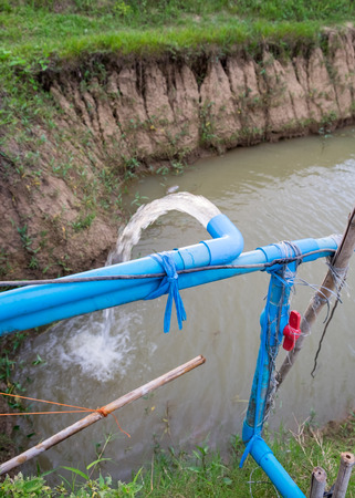 Blue pump pipe water flow down canalの写真素材