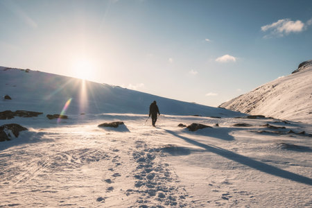 Mountaineer walking on snowy mountain with sunlight at Ryten Mount