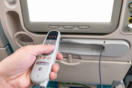 Hand holding remote with blank display on airplaneの写真素材