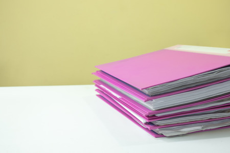 Stack of account file documents on white desk with yellow backgroundの写真素材