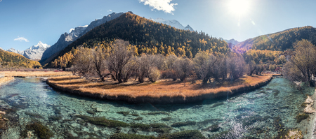 Panorama of Xiaoduo holy mountain with Chonggu temple with emerald river in autumn forest. Yading nature reserveの写真素材
