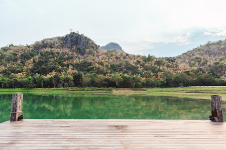 Empty wooden bridge or jetty with mountain on lake at eveningの写真素材