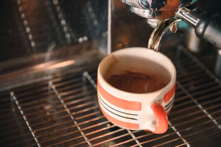 Coffee maker machine grinder pouring coffee in mug shotの写真素材