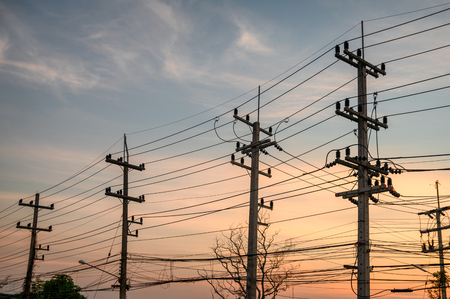 Rural rows of electricity pole with wires network on sunsetの写真素材