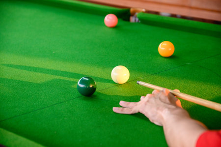 Man's hand playing snooker in bar with color snooker ball