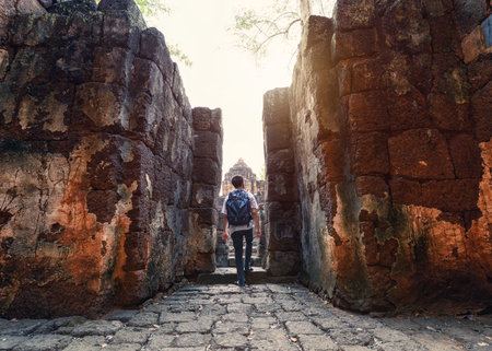 Man backpacker walking inside in Prasat Muang Sing are Ancient ruins of Khmer temple in historical parkのeditorial素材