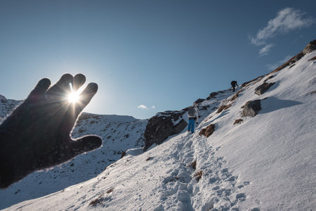 Hand wearing glove covering on the sunstars at mountain summit