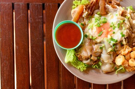 Stir-fried rice noodle with chicken, squid, fry egg and lettuce on plateの写真素材