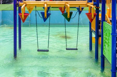 Swings hanging on amusement waterpark with pool and water splashingの写真素材