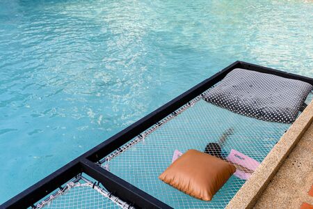 Relaxation mesh seat with pillows jut out on swimming poolの写真素材