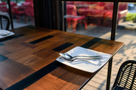 White dish with fork and spoon on wooden dining table in restaurant