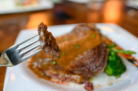 Fork dipping grilled rib eye beefsteak sliced with medium rareの写真素材