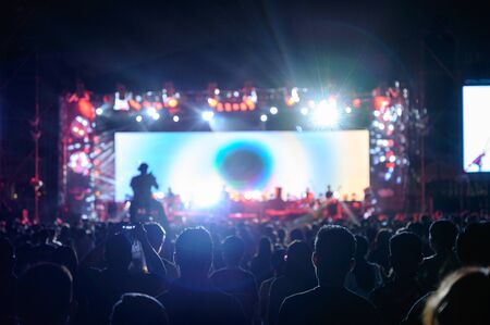 Silhouette youth audience are watching the night concert of stage lightの写真素材
