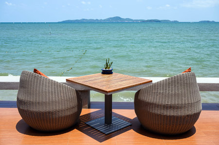 Modern weave chairs with wooden table on patio in tropical sea