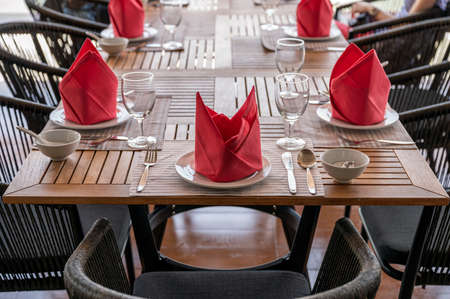 Set of wooden dining table with crockery, wine glass and red napkin in restaurantの写真素材