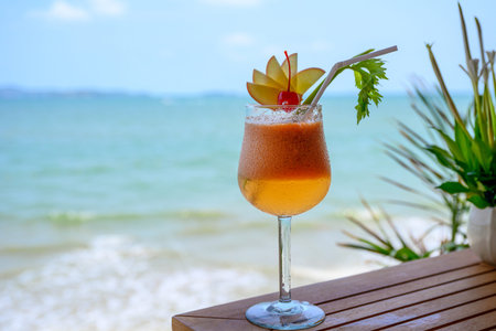 Apple mocktail with cherry in wine glass on wood table in tropical sea