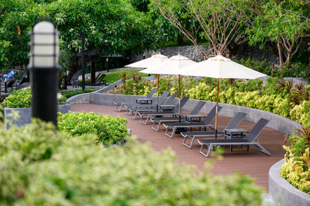 Relax sunbeds with parasol on wooden patio at poolside in garden