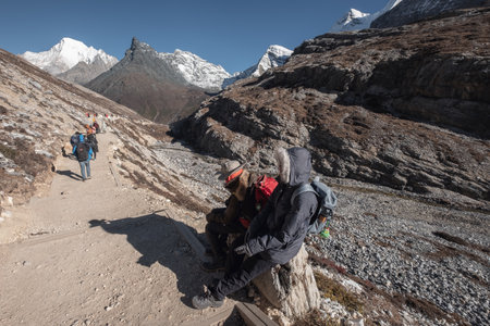 Daocheng, China - Oct 23 2018 : Travelers sitting while on rock with tourists trekking in valley at Yading nature reserveのeditorial素材