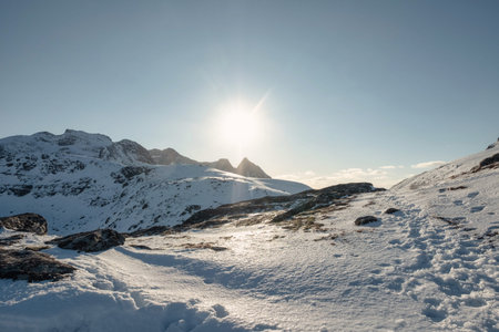 Sunset shining over snowy hill on Ryten mount in Lofoten islands