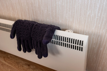 Knit winter gloves drying on convector heater