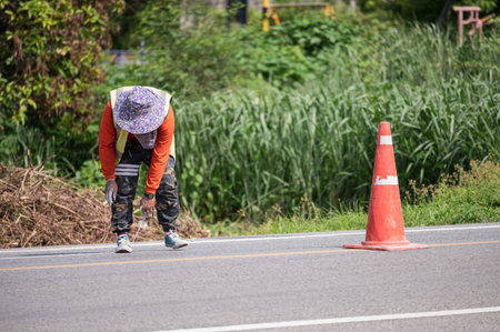 Worker wearing orange uniform is striping with measuring on the road