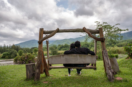 Rear of young couple sitting on wood swing in national parkの写真素材