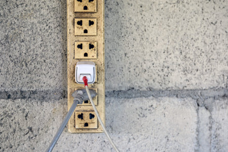 Old power electric plug with charging cable on brick wall
