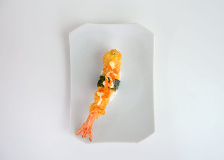 Deep fried shrimp tempura sushi nigiri with breadcrumbs and seaweed on white plate