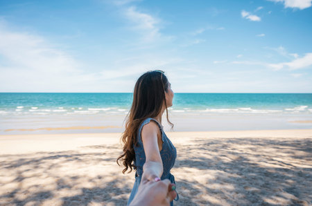 Beautiful young asian woman holding hands with boyfriend on the beach in tropical sea at vacation....