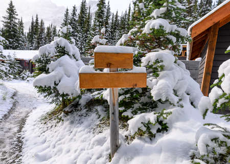 Snow covered on empty wooden signpost on cottage in winterの写真素材