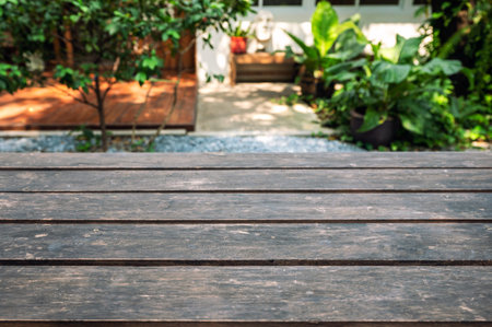 Rustic brown wooden table top on blurred green plant in garden backyard on sunnyの写真素材