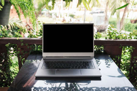 Open modern gray laptop on glass table in spring garden on sunnyの写真素材