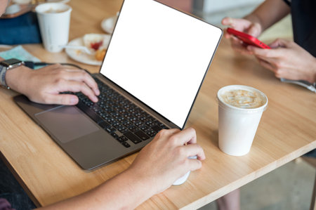 Freelance man working with laptop and coffee cup on wooden table in cafe