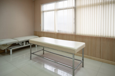 Empty patient auscultation bed with sunlight shining on curtain in ward at hospitalの写真素材