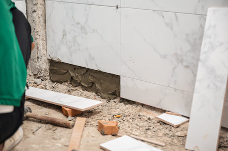 Male tiler using trowel laying marble tile with cement in bathroom. Housing development, Interior improvement renovationの写真素材