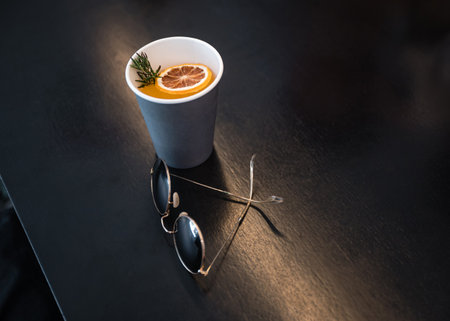 Retro glasses with orange coffee in paper cup on wooden tableの写真素材