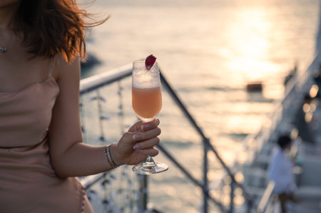 Woman in dress holding mixed cocktail on rooftop bar of cruise at evening