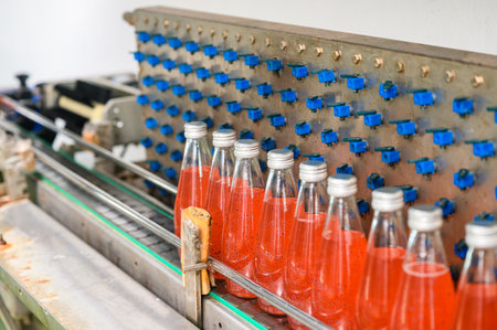Automated production line of bottled juice beverage moving on conveyor belt in beverage processing factoryの写真素材