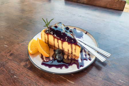 Blueberry cheesecake with biscuit, jam and orange in dish on the tableの写真素材