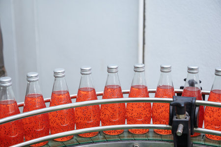 Glass bottled red juice on steel conveyor of production line in beverage processing plantの写真素材