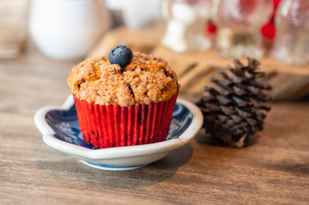 Homemade baked blueberry muffin on dish with pine cone at wooden tableの写真素材