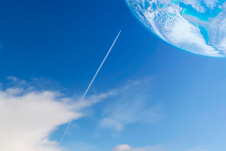A private jet plane flying with contrail or vapor trails heading to the planet on blue sky background. Elements of this image furnished by NASAの写真素材