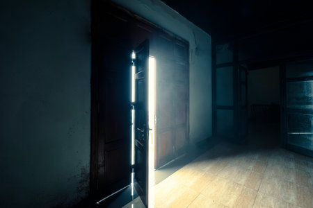 Wooden door opening with bright light shining in scary mystery darkness old roomの写真素材