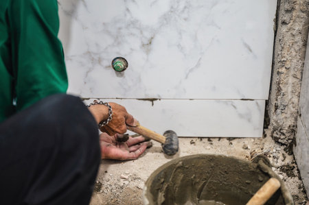 Male tiler using trowel laying marble tile with cement in bathroom. Housing development, Interior improvement renovationの写真素材